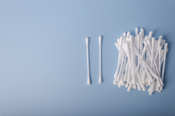 Heap of cotton swabs on light blue background, hygienic cosmetic healthcare accessory