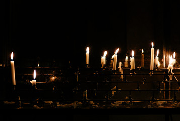 Rows of votive candles in a traditional metal holder.