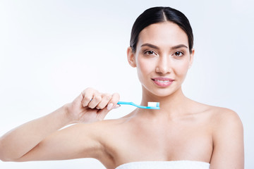 Cheerful dark-haired woman being about to brush her teeth