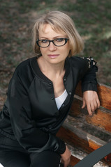 Beautiful middle-aged woman sitting on a park bench. Close-up photo.