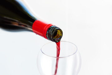 Pouring red wine from bottle into the wineglass. Blurred concept