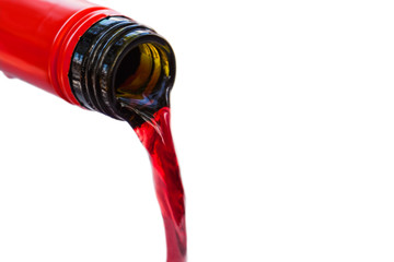 Pouring red wine from bottle on white background. Blurred concept