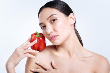 Charming brunette holding bell pepper on shoulder