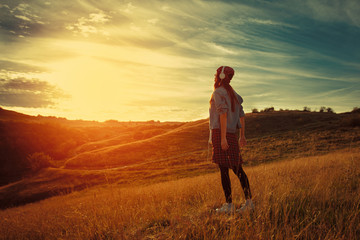 Naklejka na ściany i meble Young woman enjoys the sunset in nature