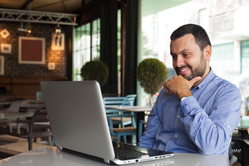 Happy handsome man looking on laptop