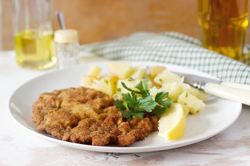 Schnitzel served with potato salad, lemon. Traditional Austrian food.