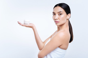 Side view of young woman holding cream on her palm