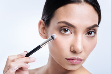 Close up of beautiful woman holding makeup brush near face