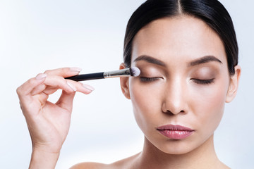 Fototapeta premium Charming woman applying eye shadows with brush