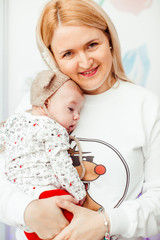 Blonde mom holds her lovely child tender standing in a room