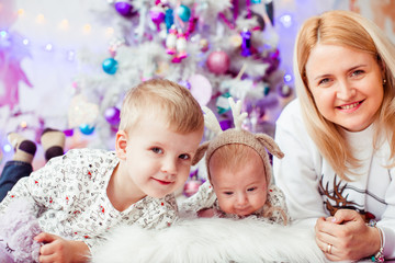 Mom lies with her sons before a Chirstmas tree