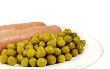Two boiled sausages with canned green peas on a white plate. Closeup, isolated on white background