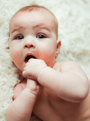 Charming little girl lies on soft beige pillow