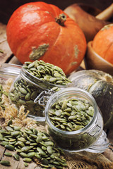 Raw pumpkin seeds in glass jars, vintage wood background, selective focus