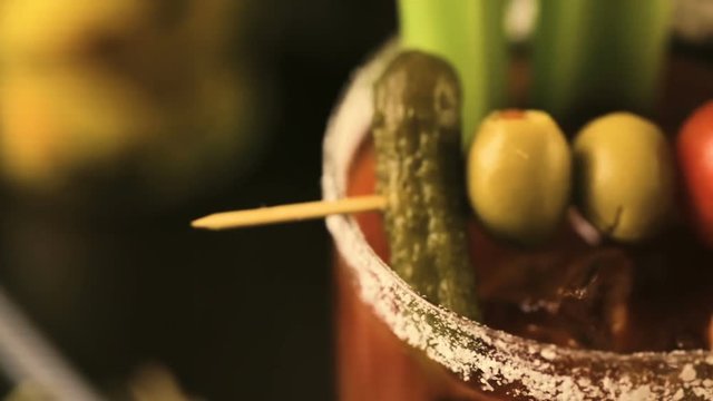 Close up of bloody mary cocktail garnished with celery sticks and olives