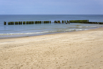 Fototapeta na wymiar Wooden breakwater of Baltic Sea seen from a beach in Dziwnowek, Poland