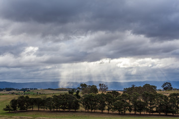 Australian countryside landscape. Sun rays protruding through storm clouds