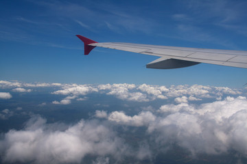 View of the clouds from the airplane window with visible wing