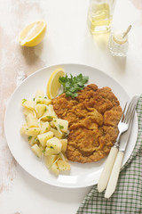 Schnitzel served with potato salad, lemon. Traditional Austrian food.