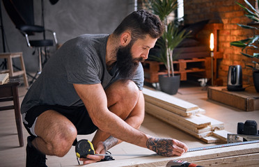 Carpenter measuring boards in a room with loft interior.