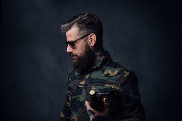 A man dressed in military shirt, drinks craft beer.