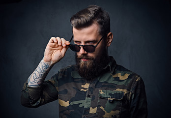 Fototapeta premium Portrait of bearded tattooed hipster male dressed in a military 