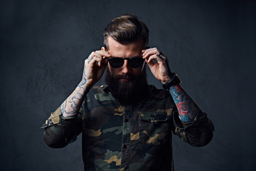 Portrait of bearded tattooed hipster male dressed in a military 