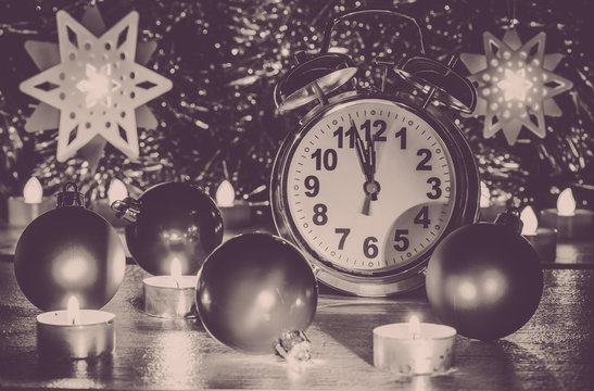 Christmas composition with alarm-clock, balls and candles. Photo b/w, toned