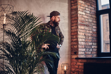  Bearded man posing over the wall in a room with loft interior.