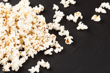 Popcorn horizontal banner. Red stripped paper cup and kernels lying on dark background. Copy space.