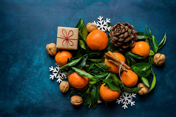 Bright Tangerines Green Leaves Pine Cones Gift Box Snow Flakes Ornaments on Dark Blue Background....