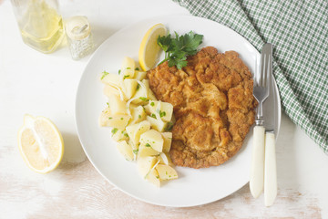 Schnitzel served with potato salad, lemon. Traditional Austrian food.