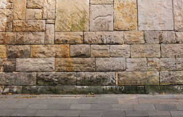 wall of granite blocks and a pavement fragment with a small amount of dry leaves