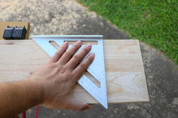 Hand of carpenter is measuring angle of wooden furniture
