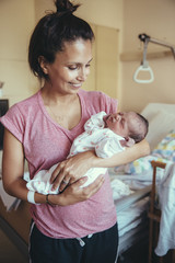Obraz na płótnie Canvas Happy mother holding her newborn baby in hospital
