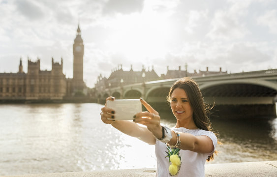 UK, London, beautiful woman taking a selfie near Westminster Bridge