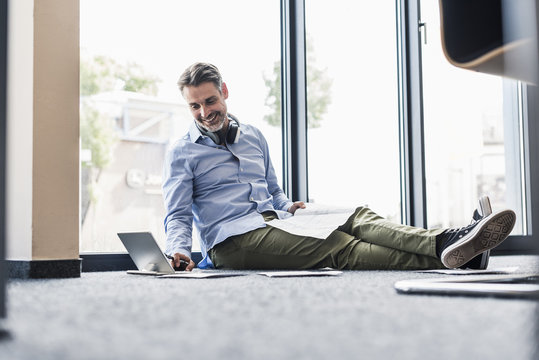 Smiling businessman working on the floor in office