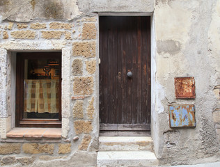 Fototapeta na wymiar Old weathered wooden door and window of rustic village house, Tuscany, Italy.