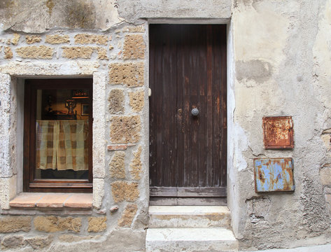Old weathered wooden door and window of rustic village house, Tuscany, Italy.