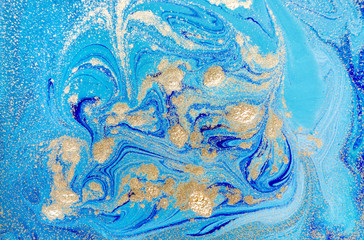 Marbled blue abstract background with golden sequins. Liquid marble ink pattern.