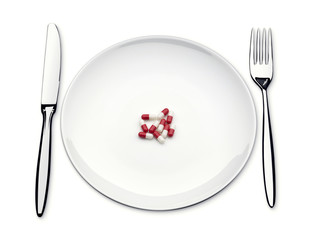 pills on an empty plate with knife and fork