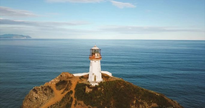 Breathtaking aerial panoramic view of cliff with lighthouse Brinera. It's octahedral tower in shape of truncated pyramid with lantern. Seashore is on background under natural sunlight. Russia. Aerial