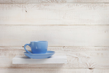 blue cup at shelf on white wooden background