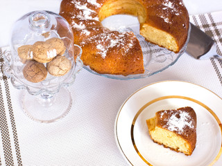 Cupcake with powdered sugar in a vase. A slice of cake on a white dish. Almond cookies in a glass vase.