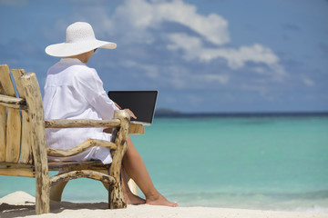 Business woman using laptop computer on the beach