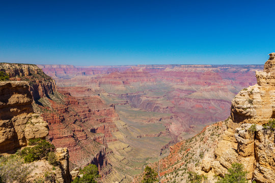 Bright scenery in the Grand Canyon National Park, with red stone formations and clear blue sky