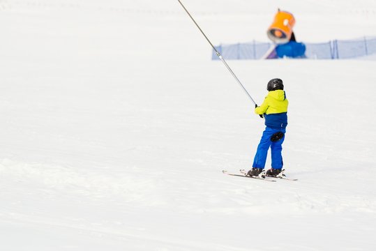 Little child going up the ski slope on ski lift.