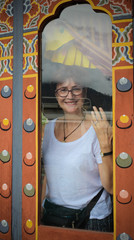 Beautiful Caucasian woman smiling behind a dirty window of a restaurant in Punakha, Bhutan.