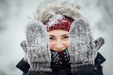 Female tourist with snow all over peeking through snowy gloves