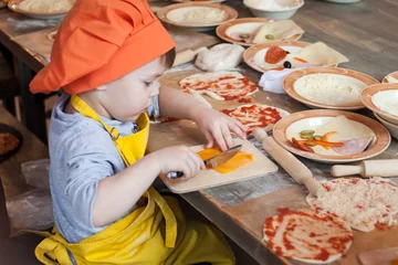 Papier Peint photo Cuisinier Petit cuisinier. Les enfants font des pizzas. Master class pour enfants sur la cuisson de la pizza italienne. Les jeunes enfants apprennent à cuisiner une pizza. Enfants préparant une pizza maison